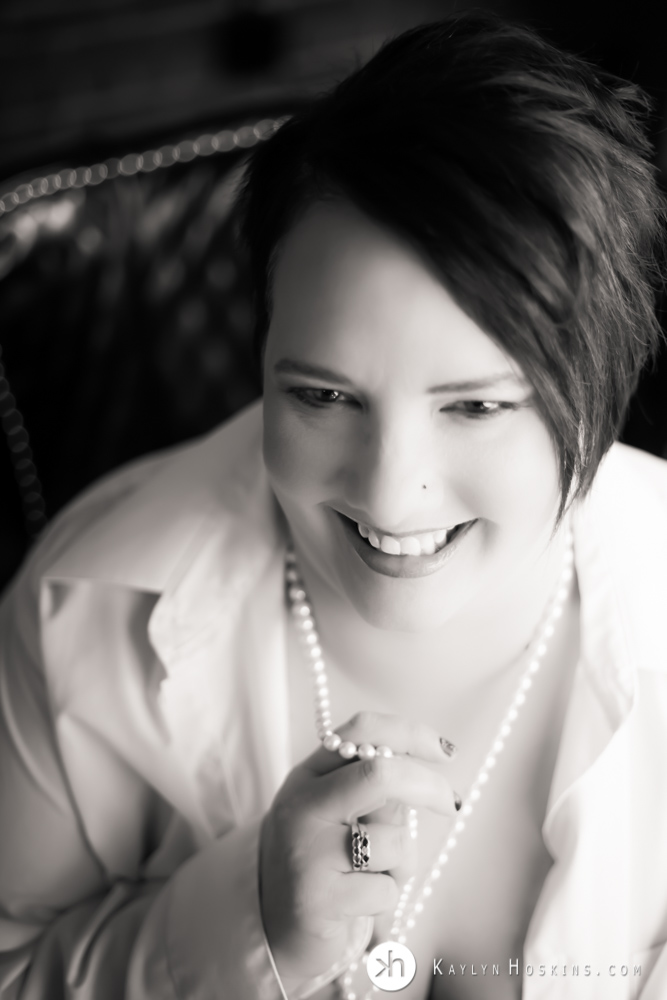 Black and white image of boudoir goddess playfully touching her pearl necklace