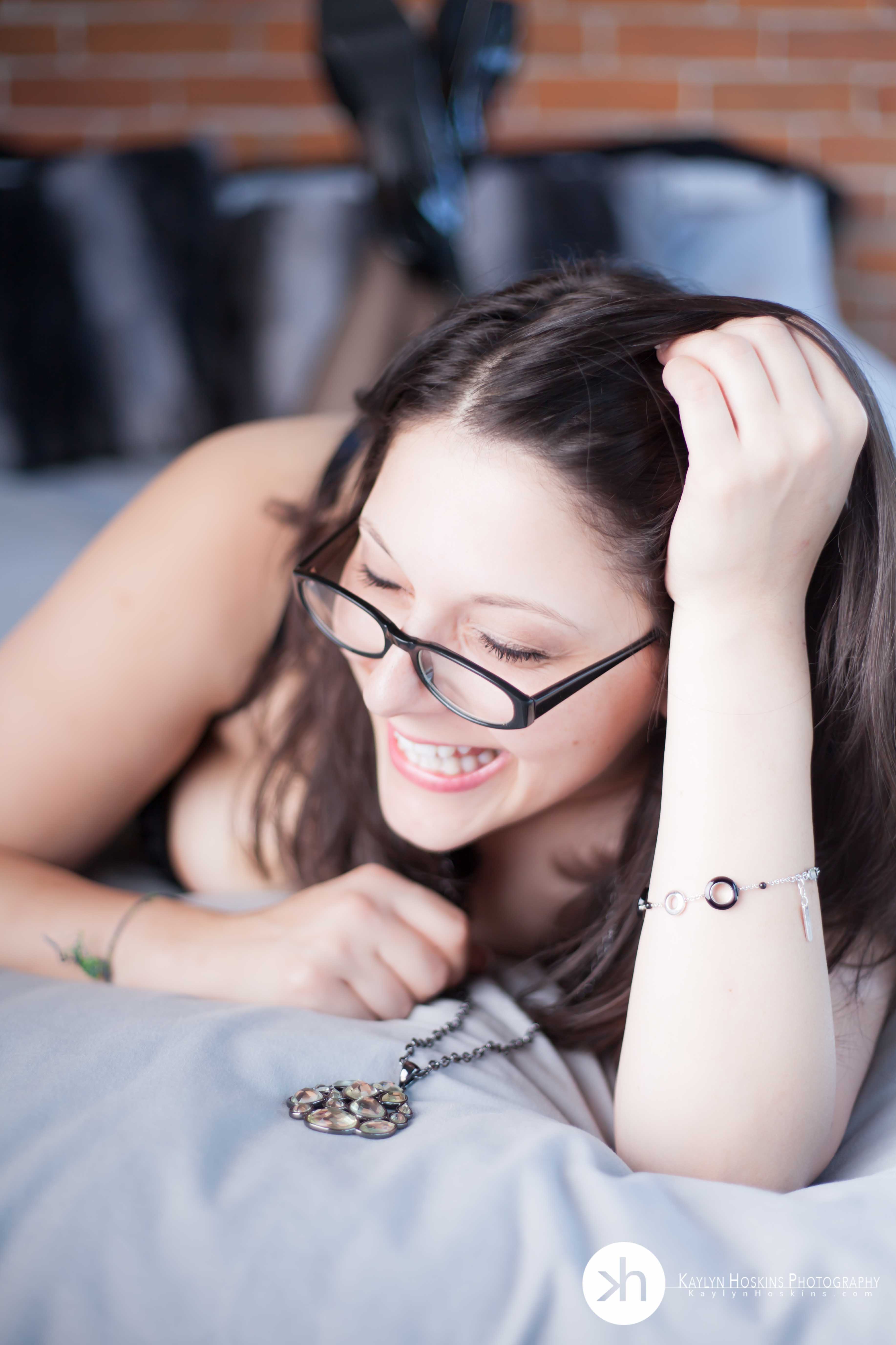 Suzie giggles while laying on bed during boudoir experience