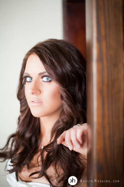 Hair & Makeup Artist Laura Rybak leans up against wooden door during boudoir experience at Kaylyn Hoskins Photography