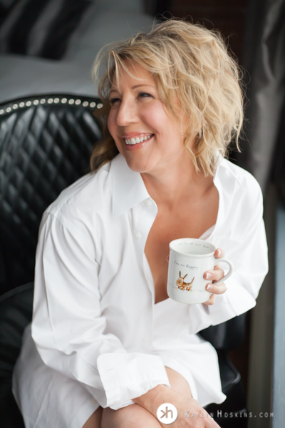 Boudoir Goddess sitting in black chair wearing her husband's dress shirt during boudoir experience at Kaylyn Hoskins Photography in Solon, Iowa