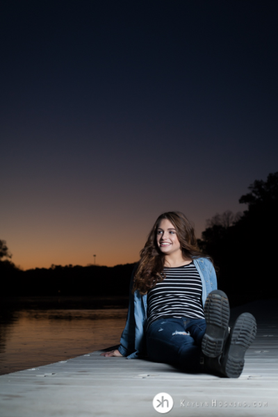 Junior Rower Aurora relaxes during sunset on the dock at P. Sue Beckwith, M.D., Boathouse during senior photo session 