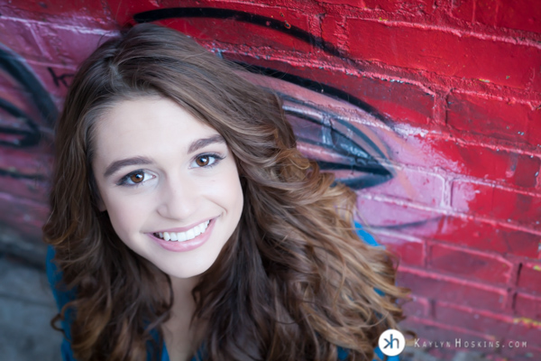 Solon Senior leans up against graffiti brick wall downtown Iowa City during senior pics  