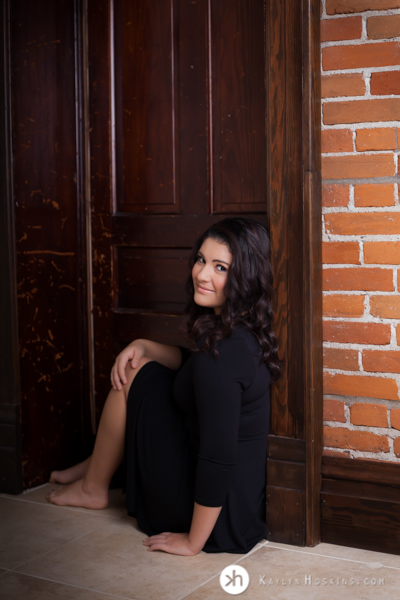 Prairie Senior sits in doorway during senior session at Kaylyn Hoskins Photography