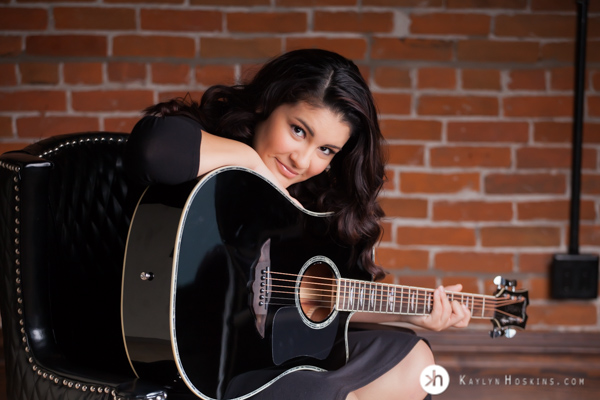 Prairie Senior Delaney leans on guitar during senior portraits in Solon, Iowa