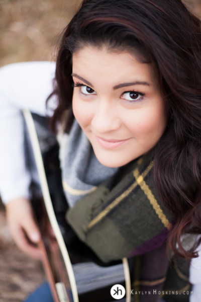 Prairie Senior looks up from playing guitar during outdoor photo session at Lake MacBride in Solon, Iowa