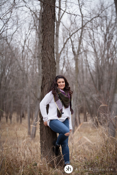 Prairie Senior Delaney leans against tree at Lake MacBride during outdoor Senior portraits with Kaylyn Hoskins Photography