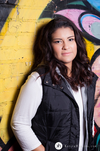 Prairie Senior Delaney leans against colored brick wall downtown Iowa City during out door senior pictures