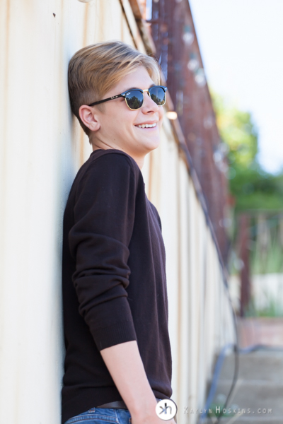 CA Senior leans against cement wall with sunglasses on during senior portrait session