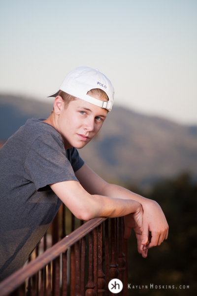 CA Senior leans on railing of balcony overlooking folsom lake during senior portrait session