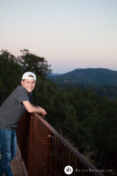 CA Senior smiles big while leaning on deck railing during senior photo session in Vacaville, CA