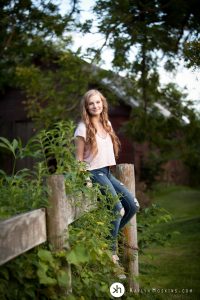 Gorgeous Senior Gracen sits on vintage fence during senior photos in solon, iowa