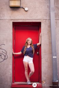 Solon Senior standing in red doorway behind University Camera downtown Iowa City