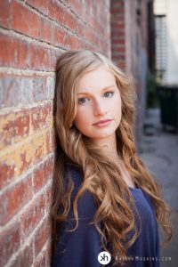 Solon Senior leaning up against brick wall downtown iowa city