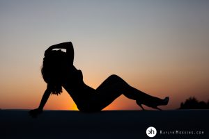 Gorgeous Boudoir goddess silhouetted against setting sun on studio rooftop in solon iowa