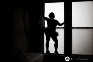 Curvy Woman silhouetted in large window wearing stilettos and tutu