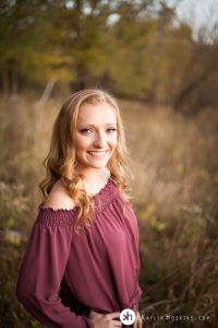 Beautiful senior smiles while standing in brush out at lake macbride in solon, iowa