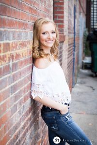 Solon Senior Leaning on brick wall downtown Iowa City during Senior Photo Session