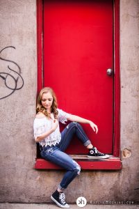 Solon Senior Olivia sitting in red backdoor of University Camera downtown Iowa City