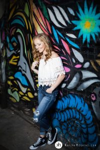 Solon Senior leaning up against colorful artistic graffiti wall behind Studio 13 downtown Iowa City