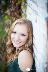 Solon Senior Liv leans up against white brick wall in downtown Iowa City Alley