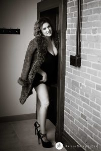 boudoir goddess standing in doorway in fur coat and black stilettos during boudoir shoot