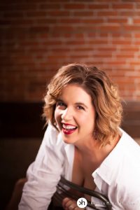 Boudoir Goddess Erin rocking red lipstick, laughing and looking at the camera