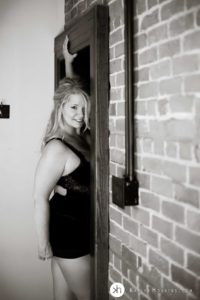 Gorgeous Blonde standing in old wooden doorway wearing black lingerie during boudoir photo shoot