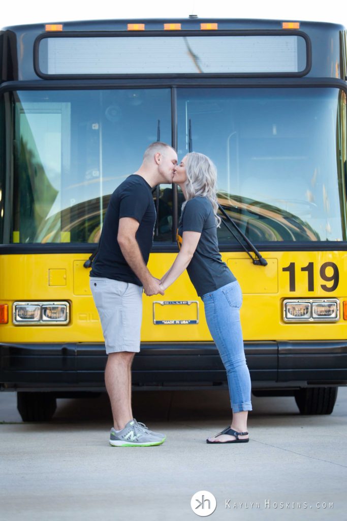 Engaged couple kiss in front of Cambus bus in iowa city, iowa