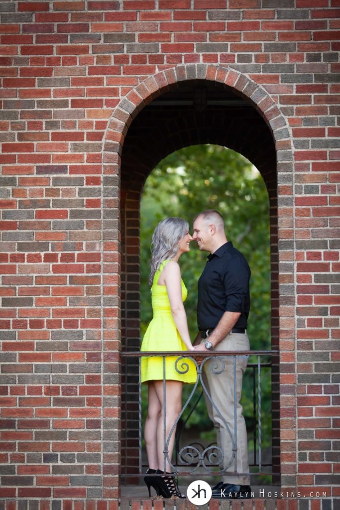 Engaged couple share an Eskimo kiss in brick arch in iowa city