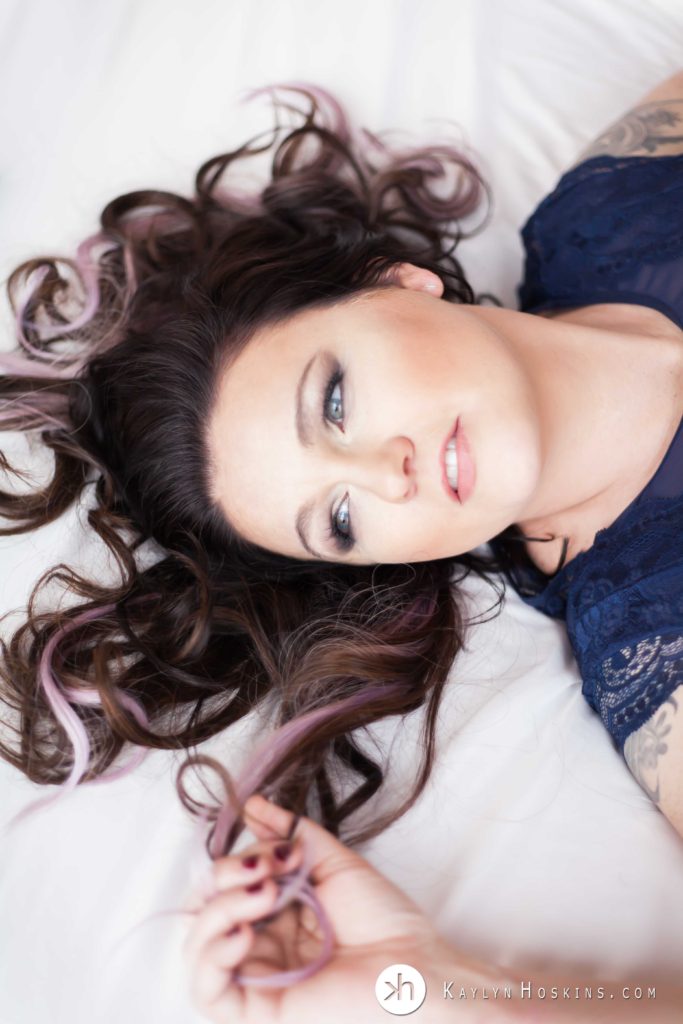 woman laying on bed looking away from camera with her hair sprawled out during boudoir shoot