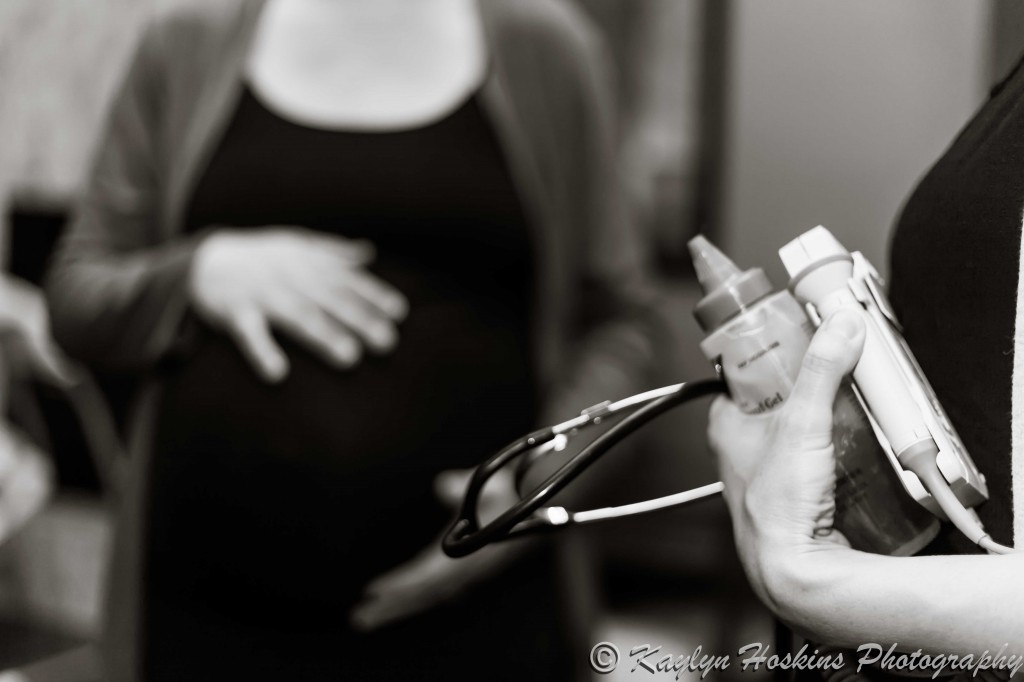 midwife's hand full of supplies with prego mama belly in background