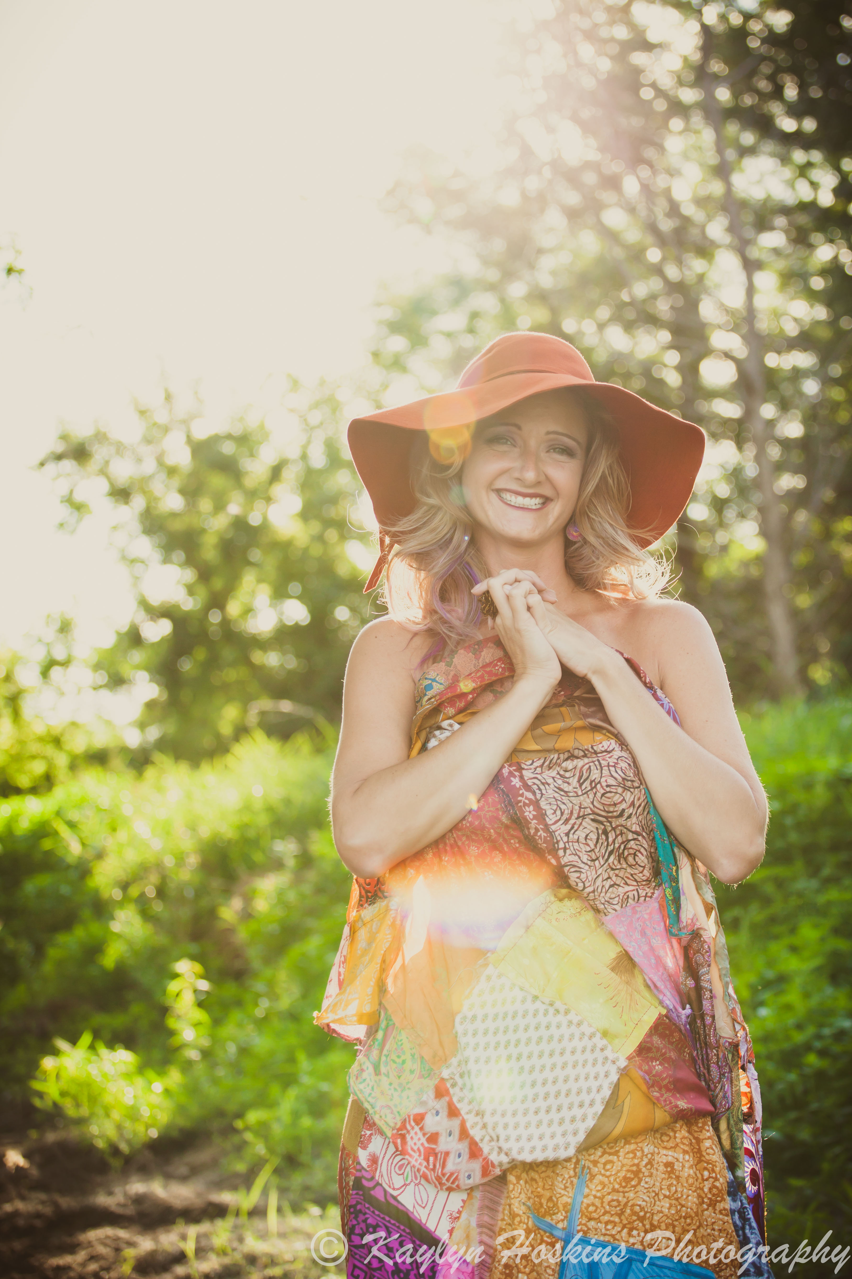 Woman in orange hat covering up with her long skirt during outdoor boudoir experience