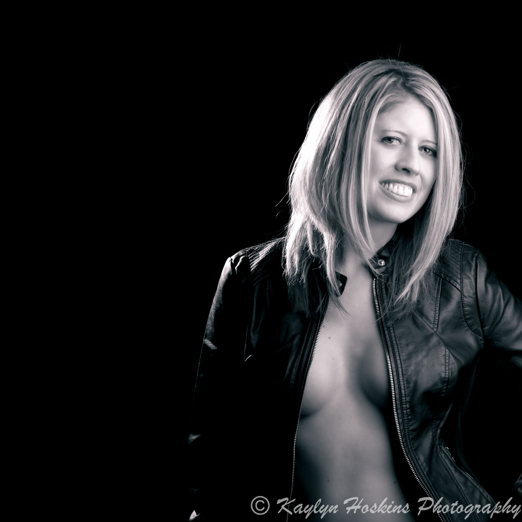 Gorgeous woman wears only a smile and leather jacked during boudoir experience