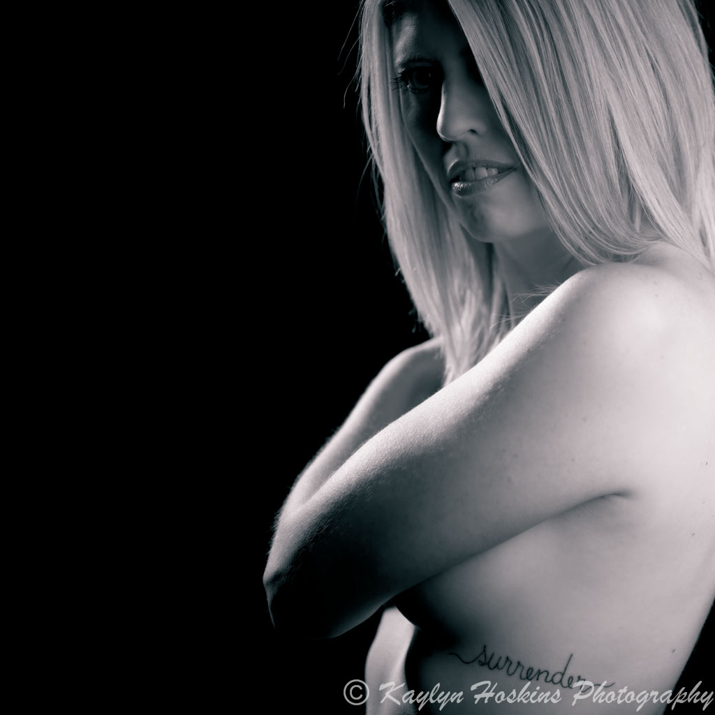 Gorgeous woman covers her breast with her arm during her boudoir experience