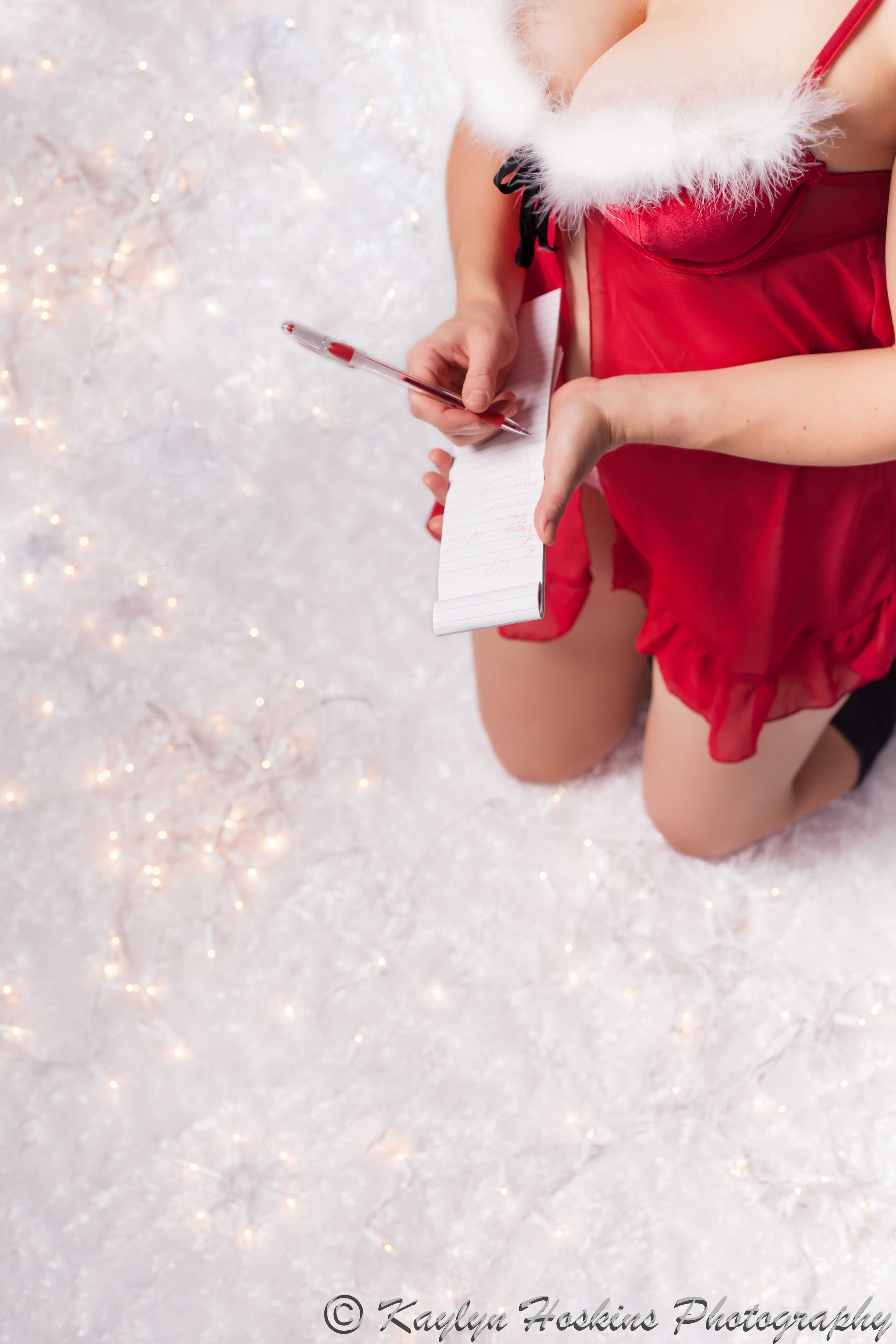 Boudoir babe wears christmas lingerie while writing a 'naughty' list