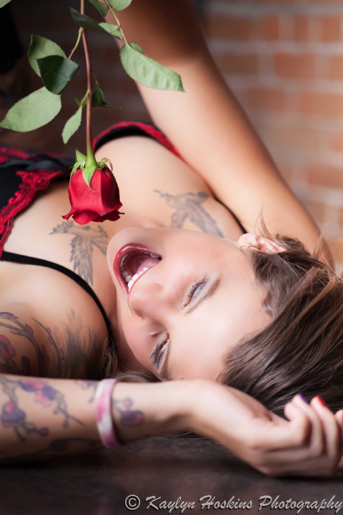 Beautiful woman laying on bar holding rose as if the is singing into it in Solon
