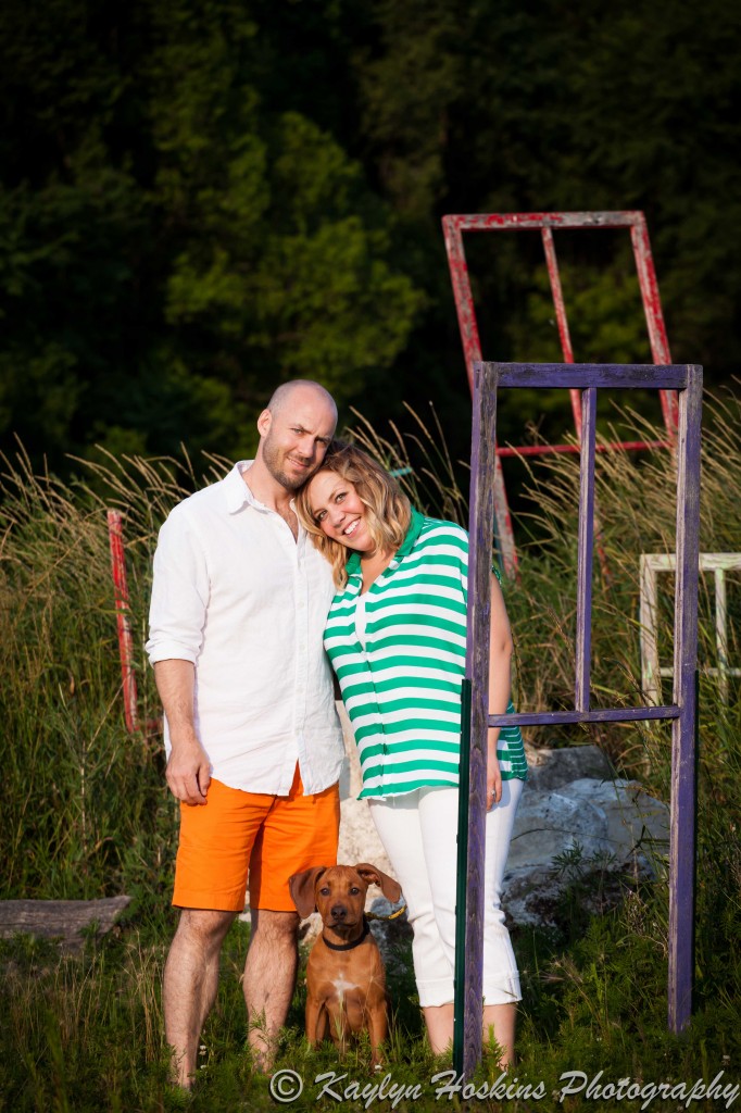 Engagement couple pose with puppy in front of old door frames in New Bo District, Iowa