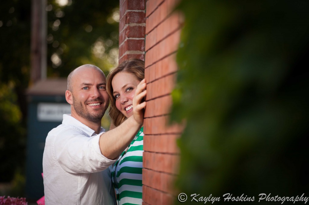 engagement couple peak out of doorway in New Bo Area during engagement photo shoot