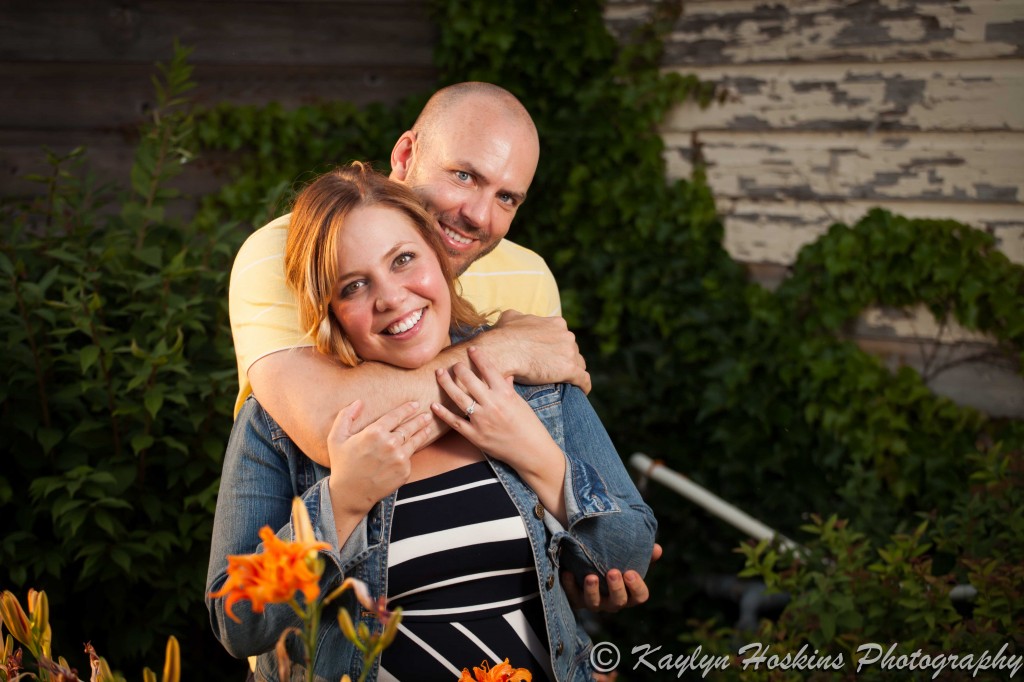 Man wraps his arms around his fiance during engagement photos in New Bo District