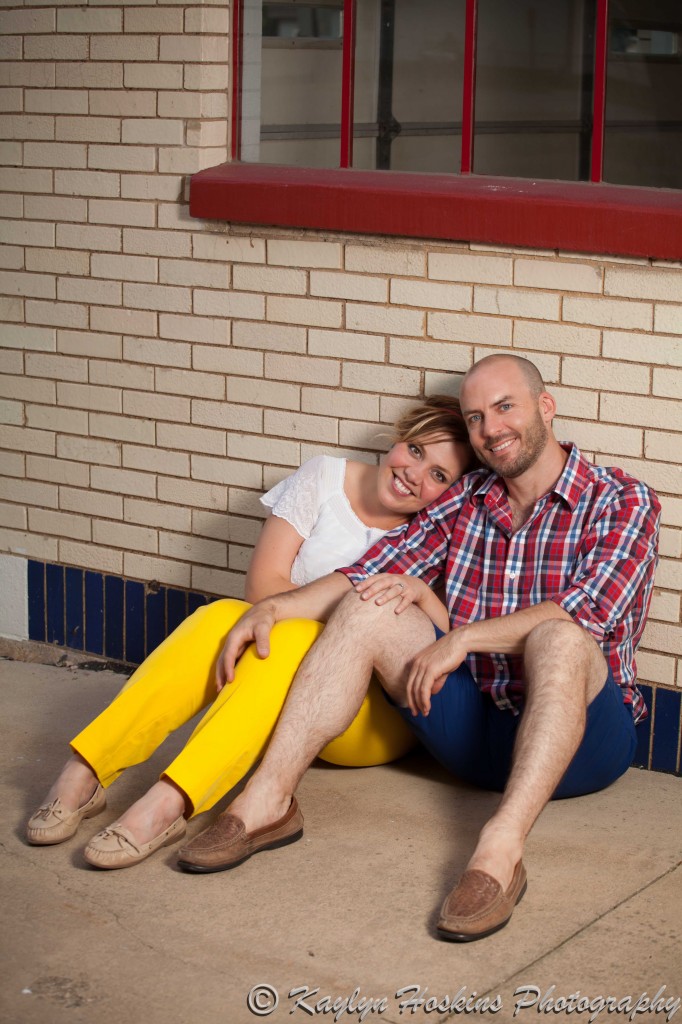 colorful engagement couple sitting against matching wall in Cedar Rapids Iowa