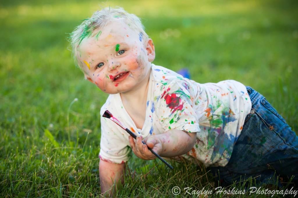 1 year old left handed artist holds paint brush during family photos with Kaylyn Hoskins Photography