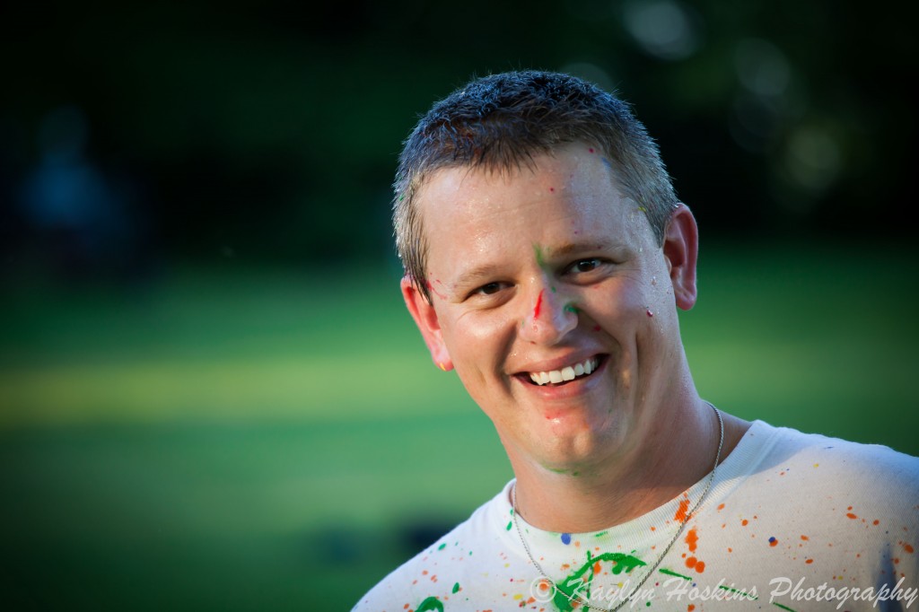 Dad smiles with paint on face after fun paint fight during family pictures