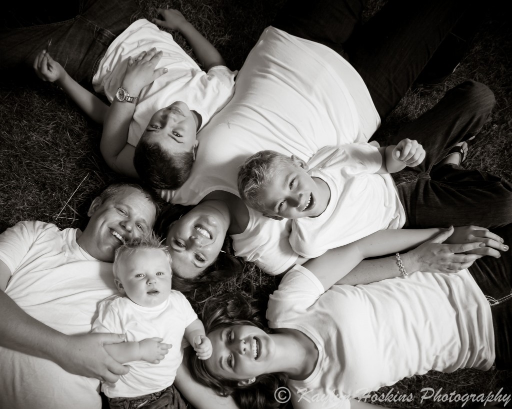 Family of 6 laugh loudly while posing for family pictures with Kaylyn Hoskins Photography