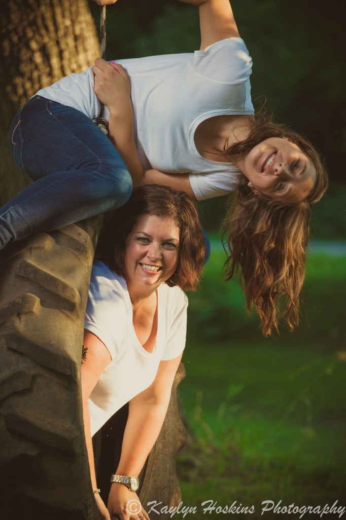 Mother Daughter smile while playing on tire swing during family photos