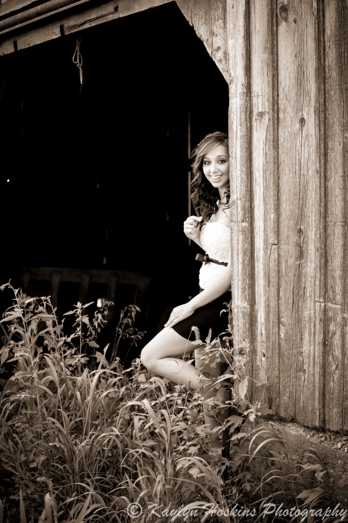 Addie peeks out of an old barn during her senior pics