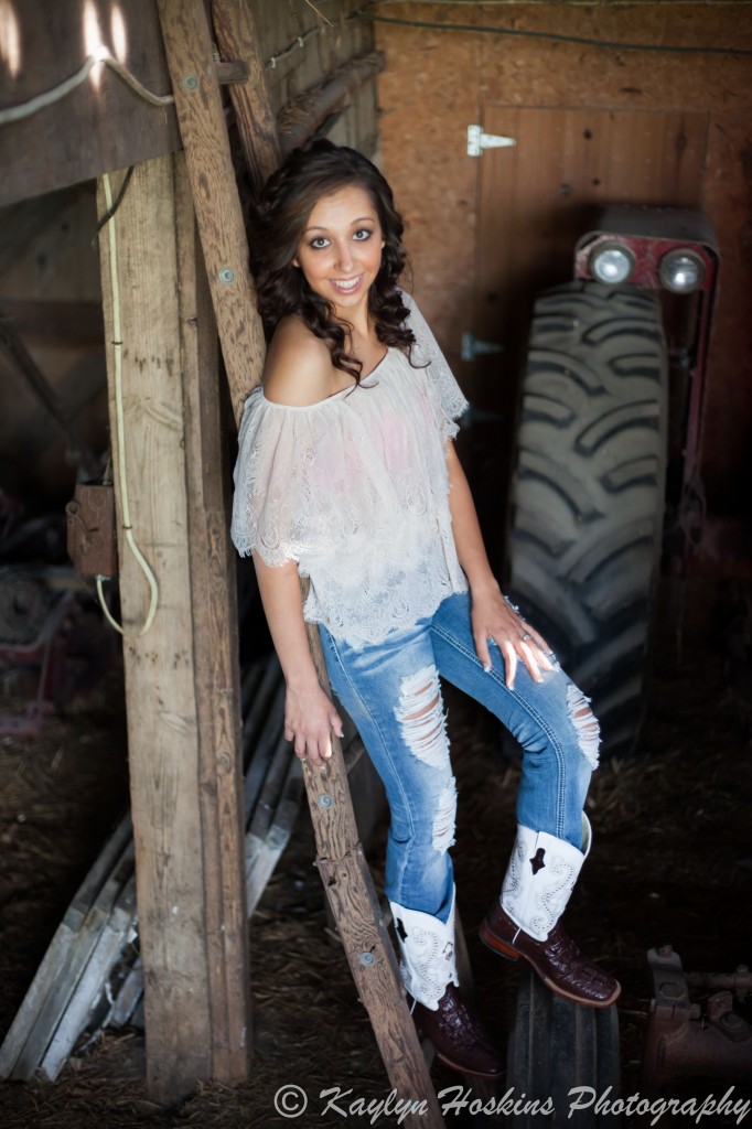 Solon senior poses on ladder in an old barn during senior portraits