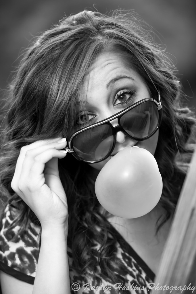 Solon Senior Addie blows a big league chew bubble gum bubble while looking over her glasses during senior pics session.