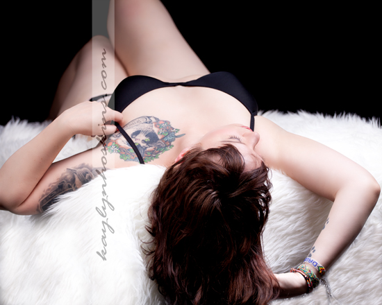 Ms. F lays on a white faux fur rug during her boudoir session with Kaylyn Hoskins Photography