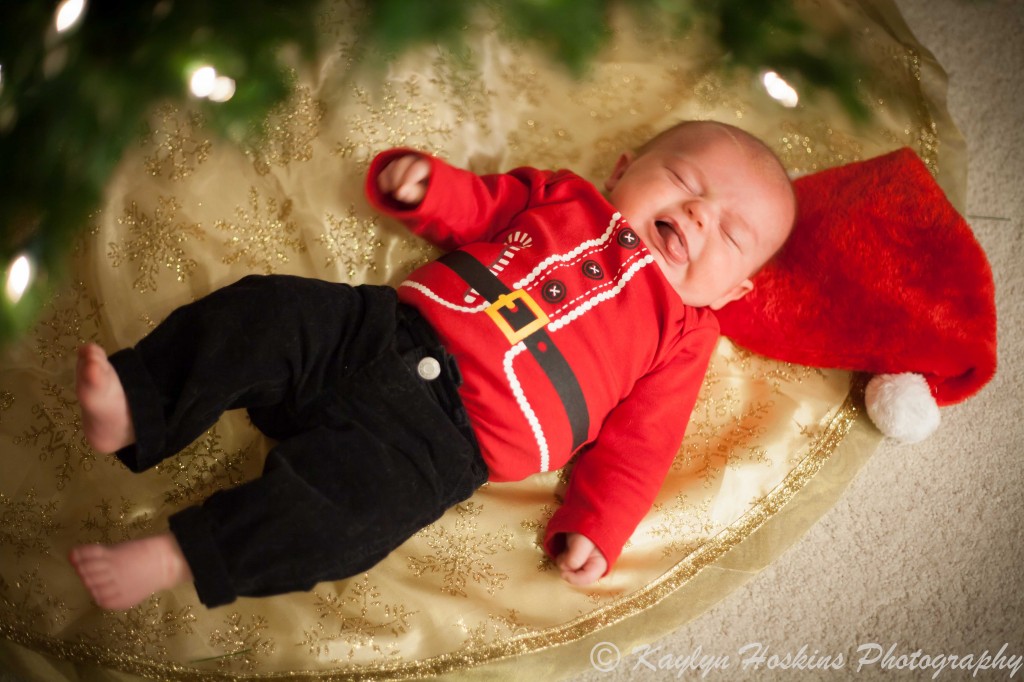 baby making fun face laying under Christmas tree