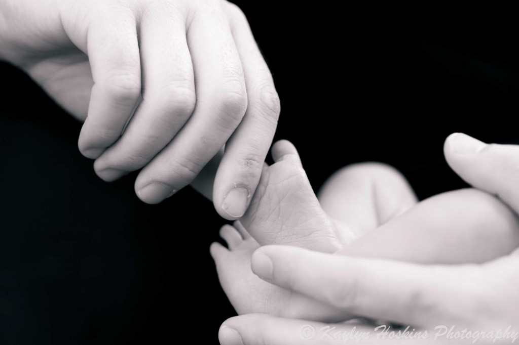 new dad playing with newborn boy's toes